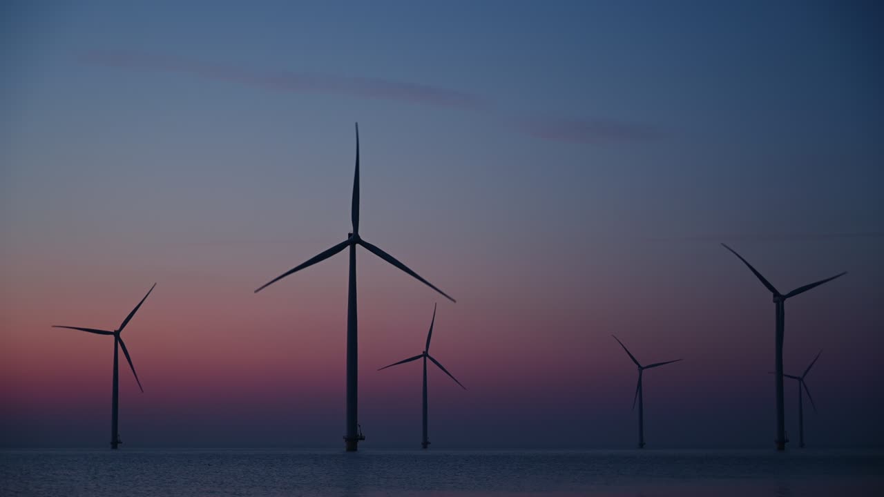 태양이 지는 동안 해상 풍력 공원에서 지속 가능한 재생 가능한 에너지를 생산하는 풍력 터빈.