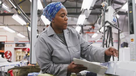 african american female car mechanic painting a body of a car