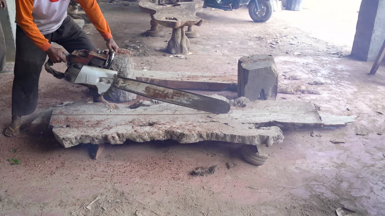 trabajador de taller de carpintería en polvo está aserrando tabla de madera con motosierra