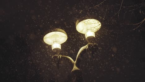 noche de navidad en el parque de invierno, primer plano de un poste de luz cálido durante la tormenta de nieve