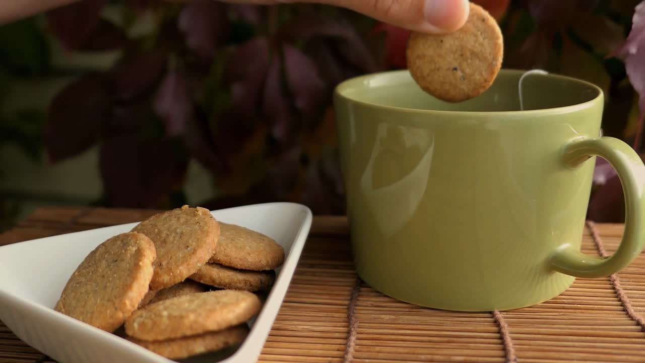 Person enjoying cookies and tea on terrace at autumn