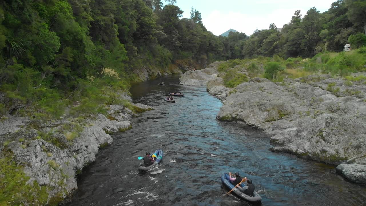 slowmo - viaje en kayak en botes de remo a través del cañón en el río pelorus, nueva zelanda con bosque nativo y rocas - dron aéreo