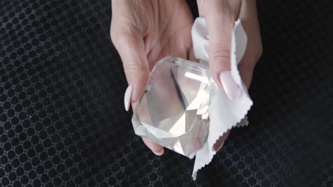 woman's hands cleaning a precious crystal piece with a chamois