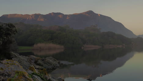 toma estática del reflejo de la montaña en la superficie inmóvil de la laguna, que muestra simetría, rocas en primer plano