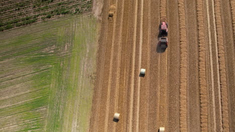 aerial top down shot of tractor harvesting agricultural field on polish countryside in summer