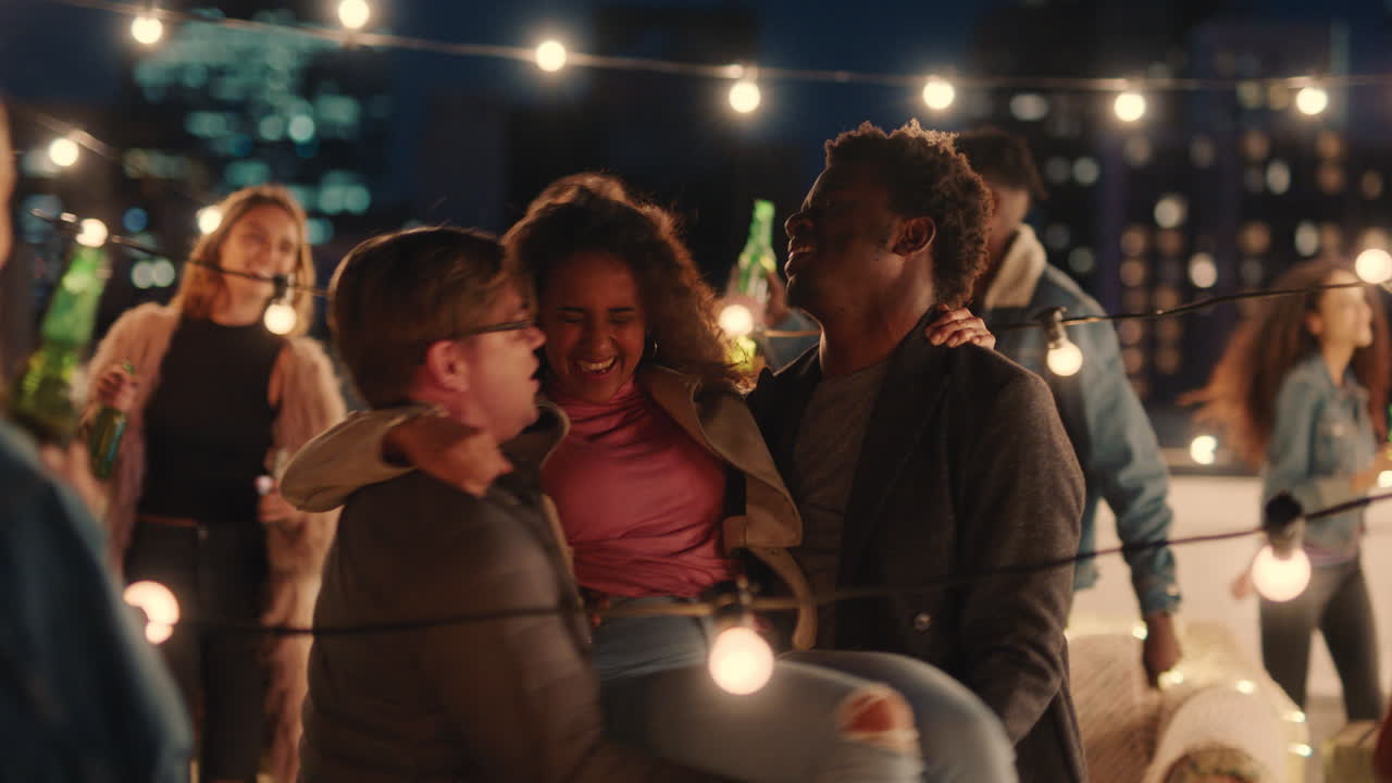 행복한 다민족 친구들이 즐겁게 놀이로 함께 춤추고 밤에 옥상 파티를 즐기고 웃으며 우정을 축하합니다.