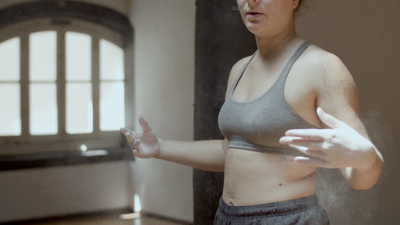 Mezza figura di pugile donna che si cosparge le mani di polvere di magnesite.