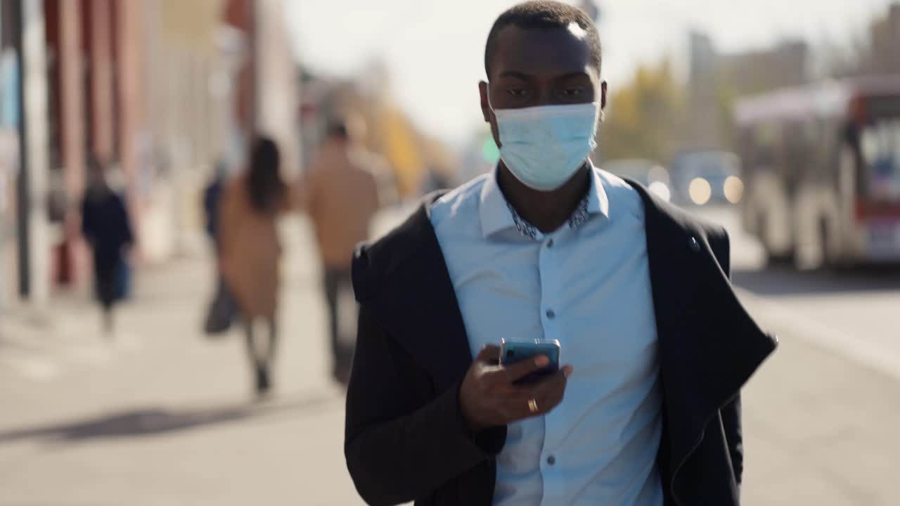 Man Walking and Using Smartphone in City Street