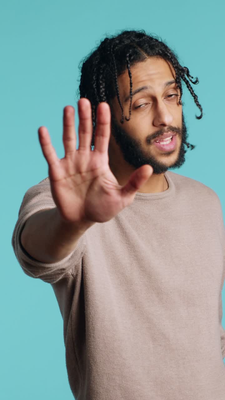 Vertical video Annoyed person doing firm stop sign gesturing, studio background