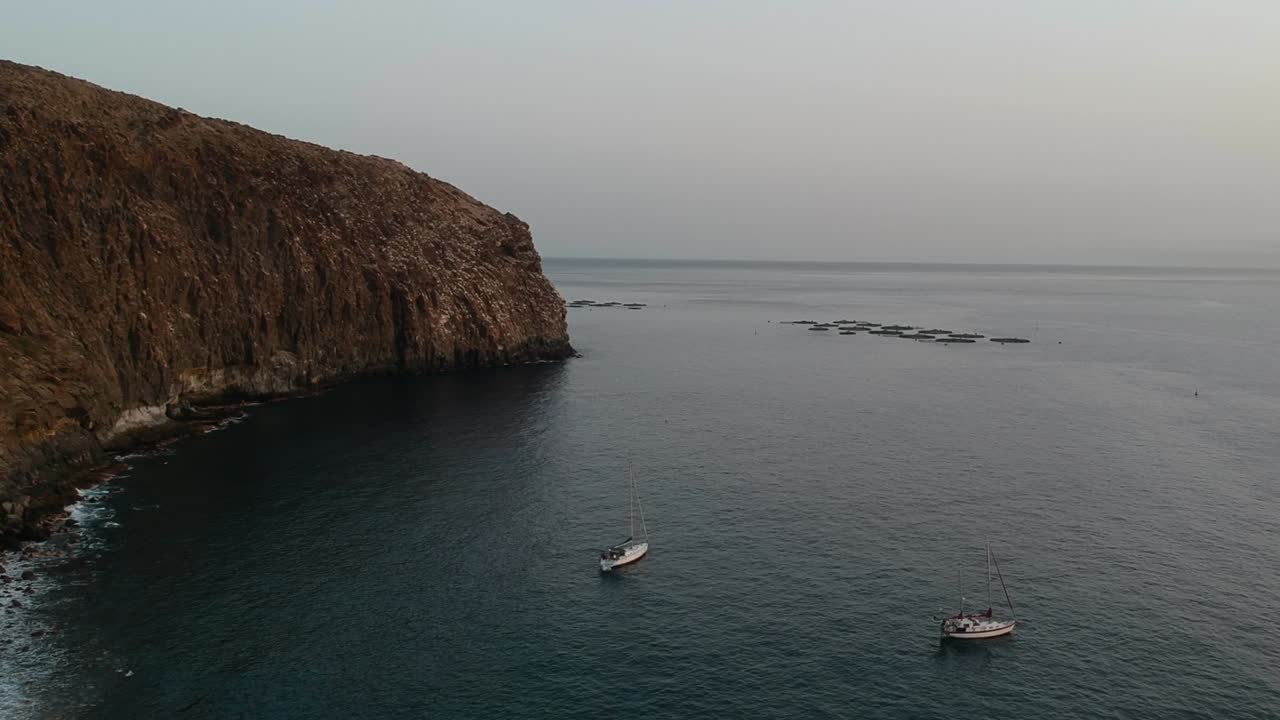Due piccole barche a vela in una cala marina di Los Cristianos, vista aerea laterale