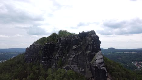 Drone-rising-up-to-iconic-mountain-rock-formation-in-eastern-Europe-on-a-bright-but-cloudy-day