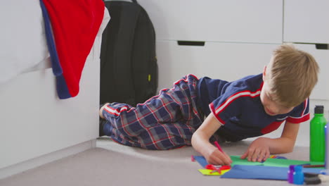 boy in bedroom making card to celebrate birthday or mothers day