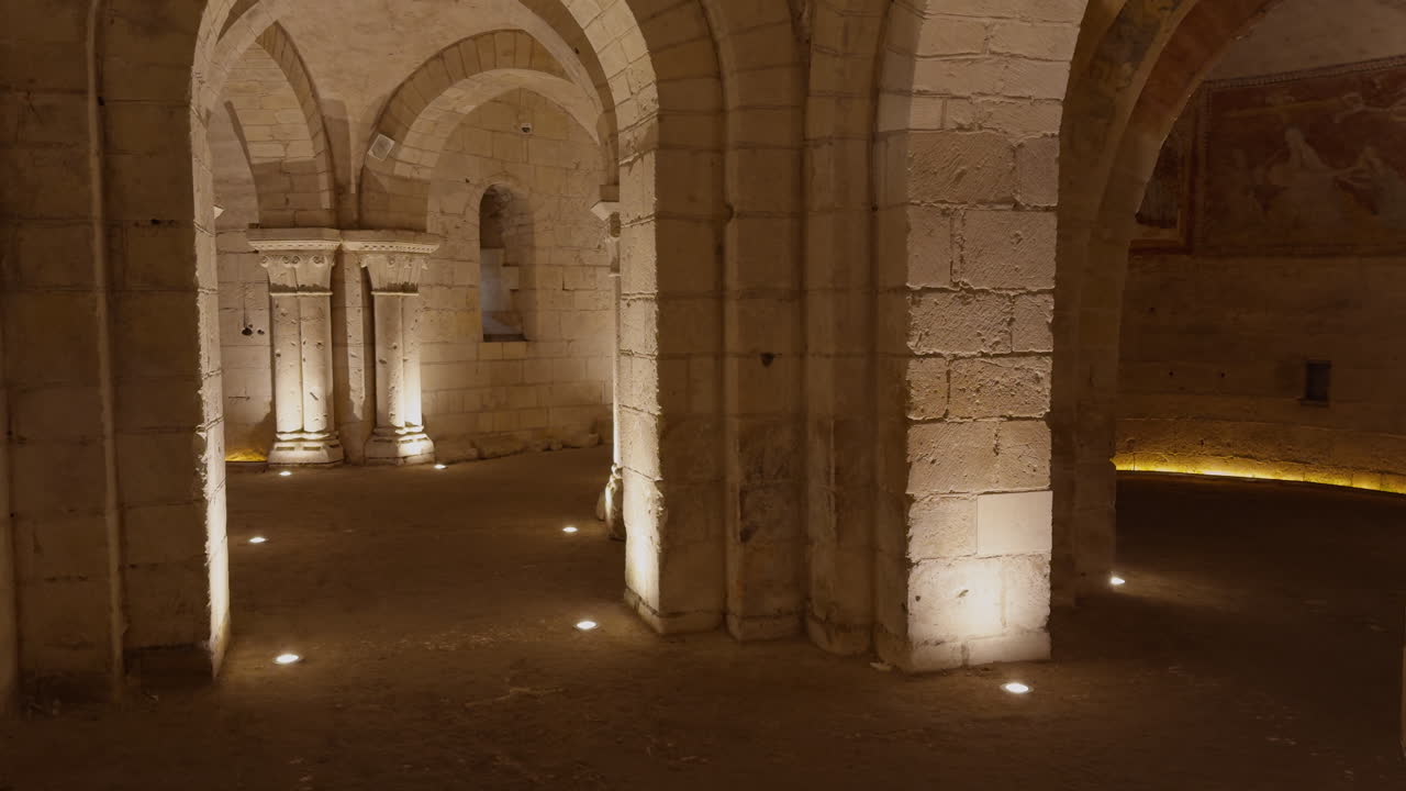 Medieval crypt with stone arches and frescoes, dimly lit with a historic ambiance