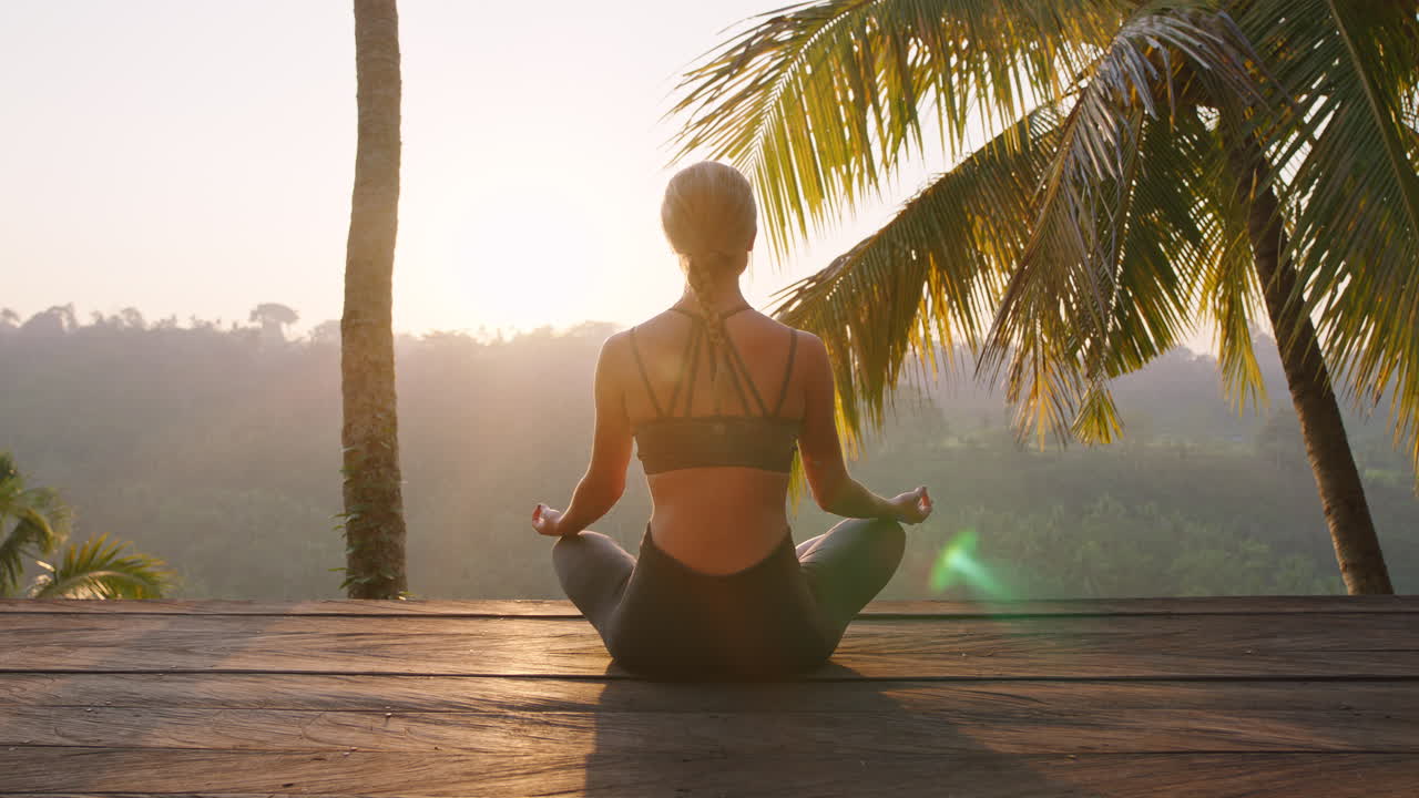 mujer de yoga meditando al amanecer practicando ejercicio de meditación de atención plena sentada en la terraza al aire libre en la naturaleza 4k