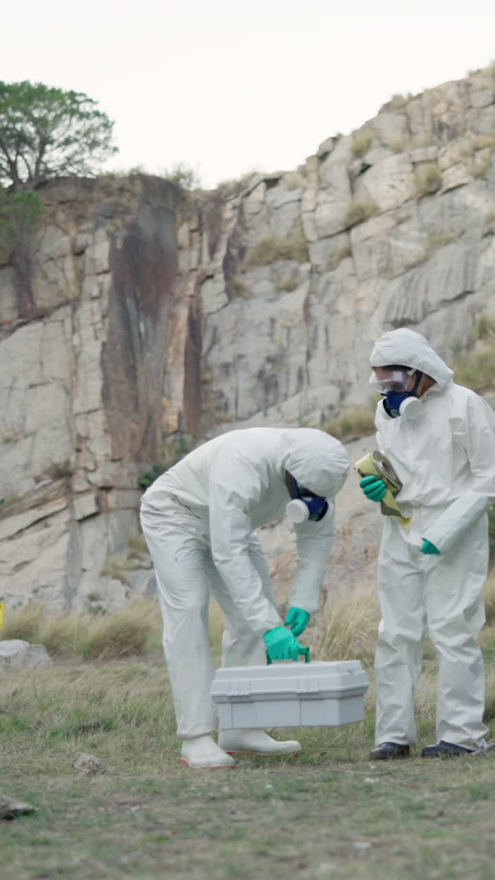 Scientists in hazard suits collecting samples in a rocky terrain