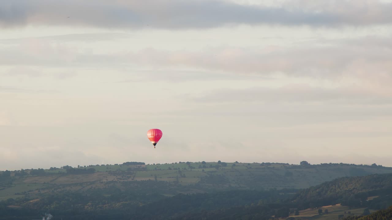 Hot air balloon decending to land in the English countryside during the early morning