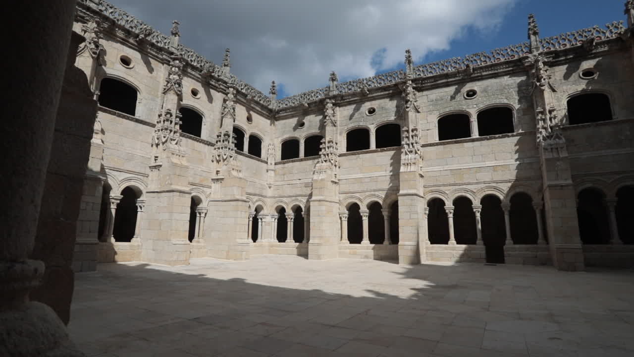 Gothic stone courtyard with intricate arches and windows, shot during daytime