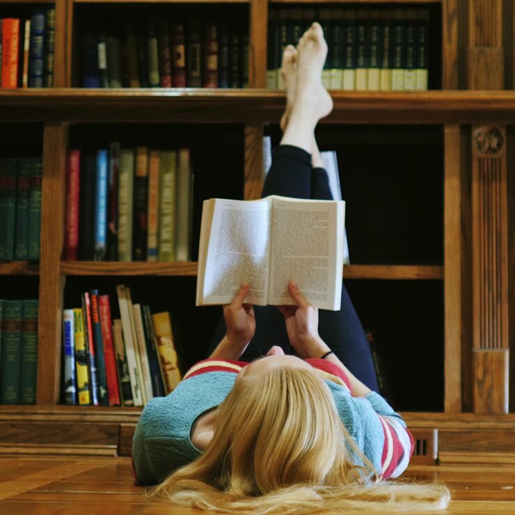 Giovane donna sdraiata che legge un libro 1