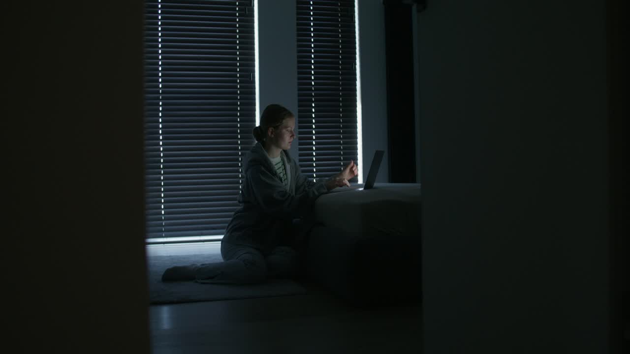 어두운 침실에서 노트북에서 일하는 여자
