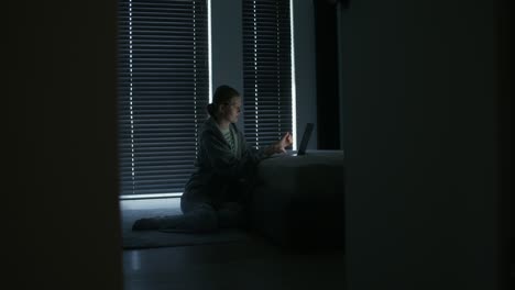 어두운 침실에서 노트북에서 일하는 여자