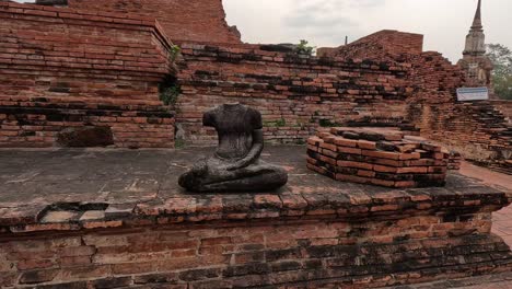 static view of a decapitated buddha statue in ruins