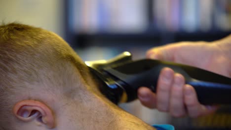 Little-boy-getting-haircut-by-his-mother-while-sitting-in-chair-at-home-during-Covid19-pandemic-lockdown