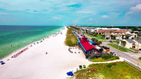 Disparo-De-Un-Dron-Volando-Por-La-Playa-De-Arena-Blanca-De-Destin-Florida-Con-Una-Vista-Del-Golfo-De-México-A-La-Izquierda-Y-El-Restaurante-Pompano-Joes-A-La-Derecha