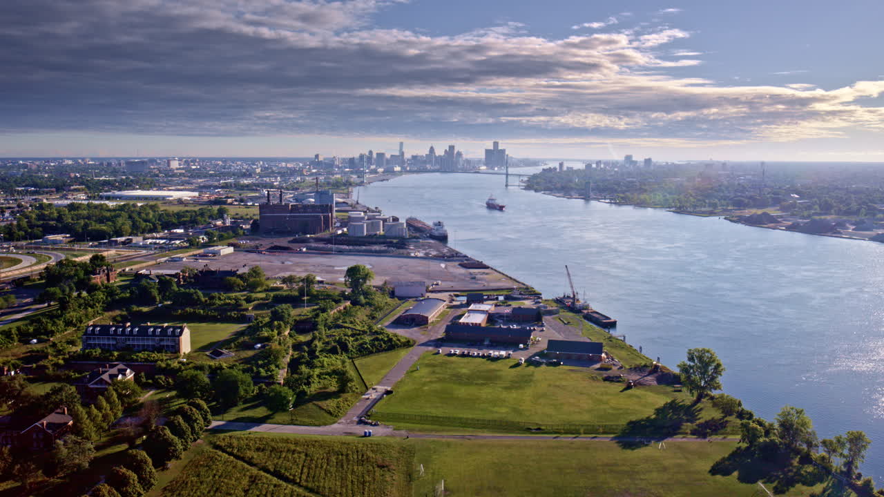 Aerial cinematic drone shot gliding over the Detroit River, showcasing the city skyline and a freighter sailing below