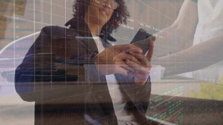 Man tapping phone on atrium landing, angling phone to share while financial charts updating