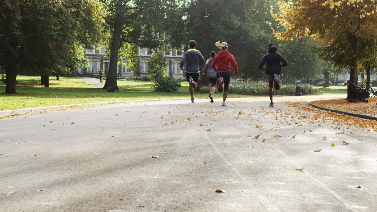 Gruppo di runner che corrono nel parco indossando tecnologia indossabile e dispositivi connessi.