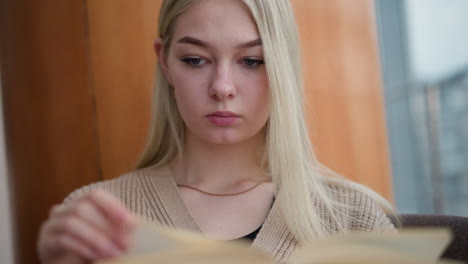 contemplative woman focuses while gently turning to a new page in a book, capturing a moment of quiet reflection, her hand interacting with the page in a soft and intimate reading gesture