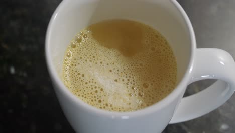 primer plano de jugo de naranja en polvo que se ha vertido en agua en una taza antes de mezclar con fondo negro