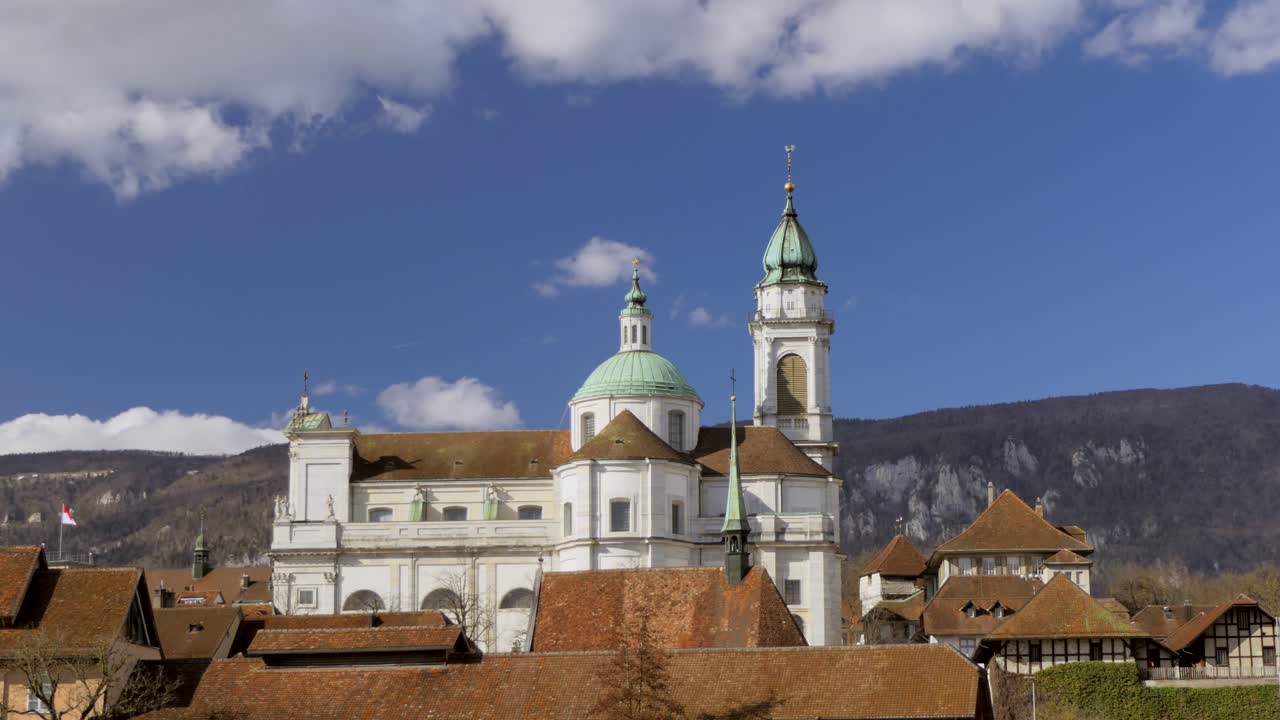 tiro de lapso de tiempo de la histórica catedral de la iglesia y nubes en movimiento en el cielo azul en el fondo en solothurn, suiza