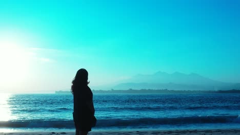 lonely girl standing in front of blue seascape with sea waves splashing on exotic beach of tropical island on a bright blue sky background, vietnam