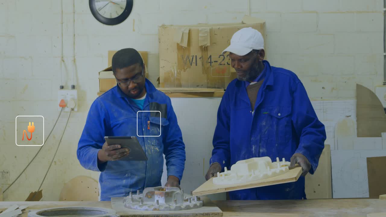 Apprentice tapping tablet while lead tilting model, numeric overlays guiding workshop review