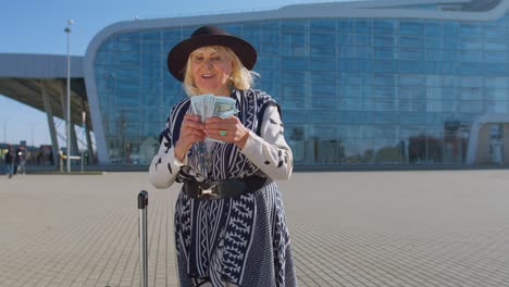 Senior-rich-pensioner-business-tourist-grandmother-stay-near-airport-hall-hold-money-dollar-cash