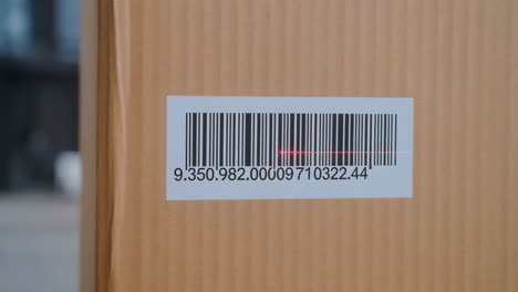 close-up of a red laser scanning a barcode on a cardboard box