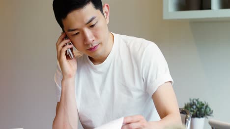 man looking at document while talking on mobile phone