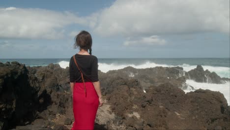 woman admires the huge waves crashing on the rocky shore