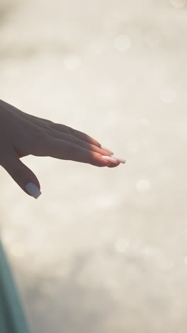 passenger holds hand out of yacht window touching water sprays on holiday trip closeup. woman enjoys freshness sailing sea on summer vacation