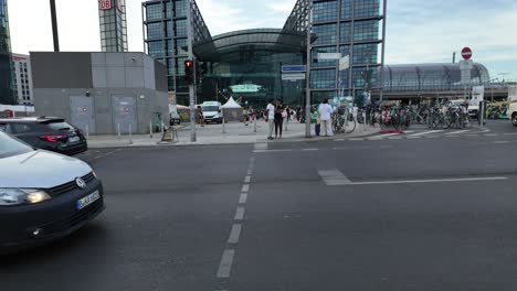 outside berlin central station showing commuters, bicycles, and modern architecture under a blue sky. tilt up