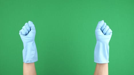 manos femeninas con guantes de goma protectores azules apretando y soltando sus dedos sobre el fondo verde chromakey. video 4k