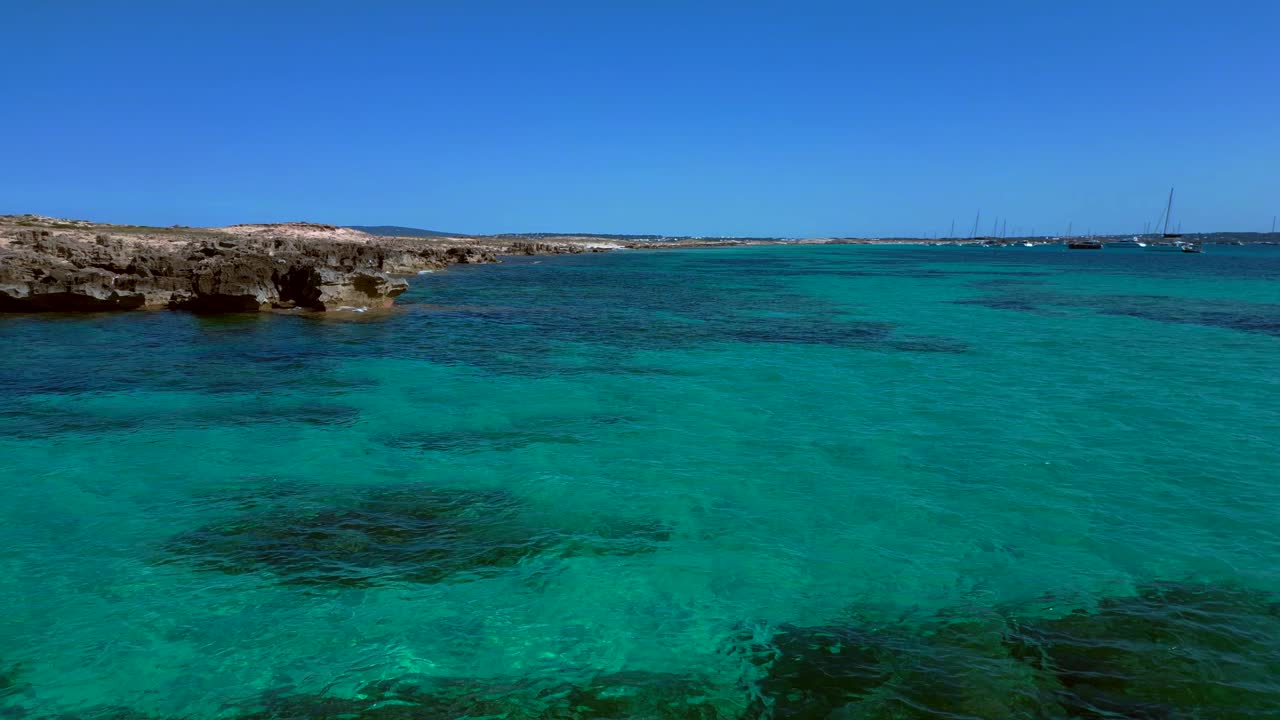 Punta des Borronar beach on Formentera Ibiza island with yachts mooring in clear turquoise water. Magic aerial view flight fly push forward overflight flyover drone