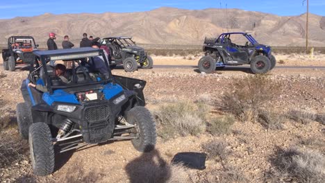 group of friends by their vehicles before off road trip on desert.