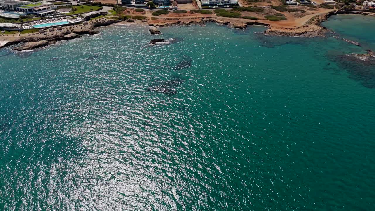 Aerial - shimmering turquoise sea and rugged coast near Chersonissos in Crete Greece