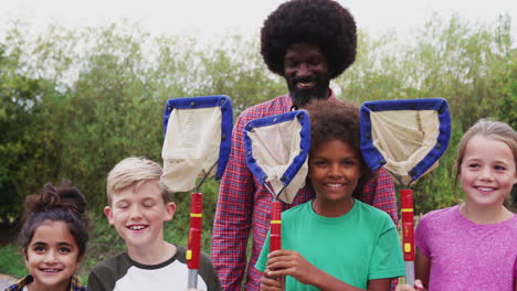 retrato del líder del equipo y del grupo de niños en el campamento de actividades al aire libre atrapando vida silvestre en el estanque