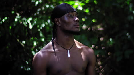 hombre afroamericano con un pañuelo negro en la cabeza con un fondo de vegetación verde desenfocado detrás