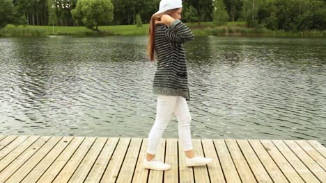 girl walking on footbridge next to a lake