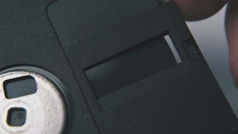 man pushes cap of diskette on clean white background