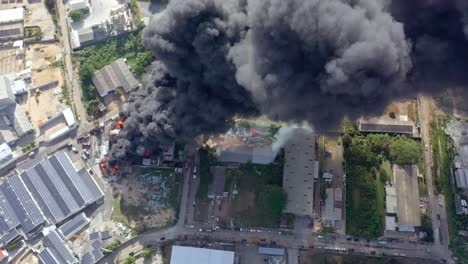 Aerial-overhead-shot-of-burning-warehouse-black-smoke-coming-out